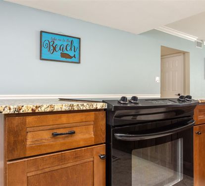 Your beach-themed kitchen awaits with granite countertops, warm wood cabinets, and a modern gas range ready for your culinary adventures.