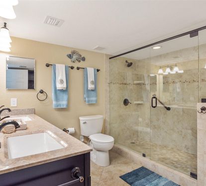 Your luxurious bathroom features a spacious glass-enclosed shower, elegant granite countertops, and soothing coastal touches that make every moment feel like a spa retreat.