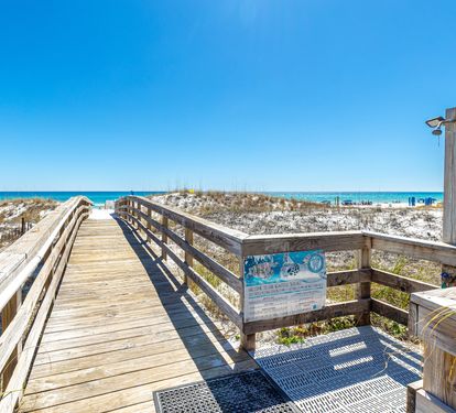 A scenic boardwalk leads through sandy dunes toward pristine white sand and turquoise waters, perfect for your daily strolls to the beach.