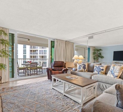 Sink into your spacious living room with plush seating, coastal decor, and balcony views that invite you to relax and unwind.