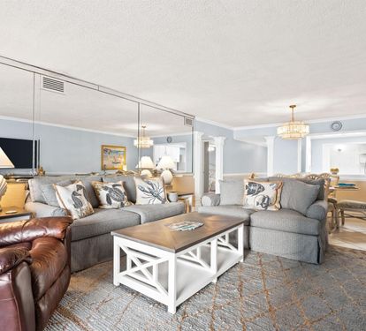 Sink into your spacious living area where coastal charm meets comfort - plush seating, nautical touches, and elegant chandeliers create your perfect retreat.