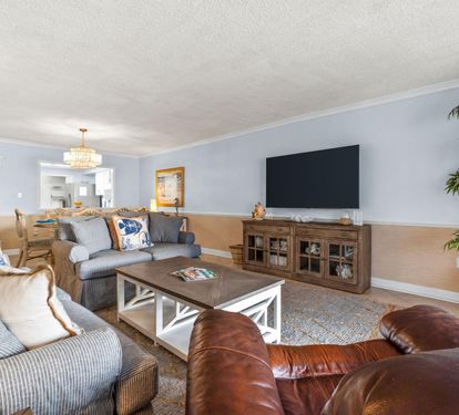 Unwind in your spacious living room with plush seating, smart TV, and elegant chandelier lighting for cozy evenings together.