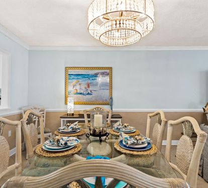 Your elegant dining room features a crystal chandelier, coastal artwork, and beautifully set table where you'll create memorable meals together.