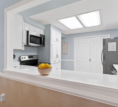 Your bright kitchen opens up with sleek white cabinets, modern appliances, and a spacious island perfect for cooking memorable meals.