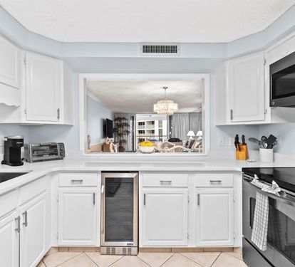 Your fully-equipped kitchen features pristine white cabinets, stainless steel appliances, and a unique pass-through window connecting you to the dining area.