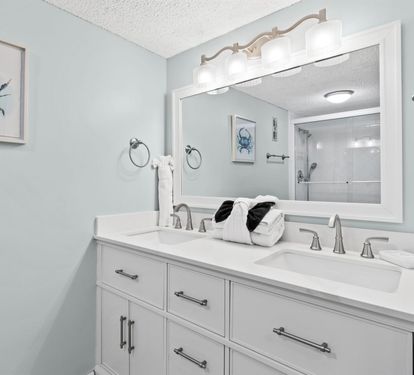 Your spacious dual-sink vanity features elegant coastal artwork and fresh towels, creating a serene morning routine space.