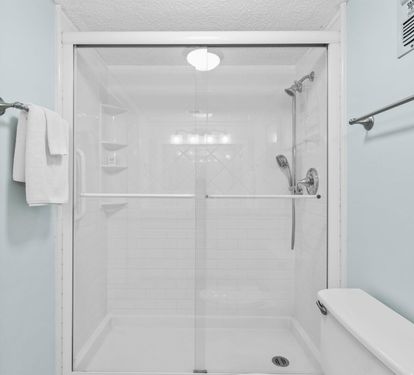 Step into your sleek, modern shower with gleaming glass doors and rainfall head—fresh towels await your refreshing retreat.