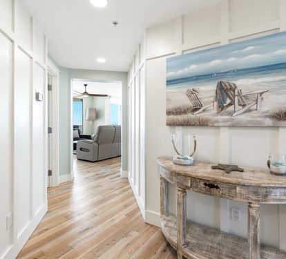 Warm coastal vibes welcome you home through this bright hallway, where beach-themed artwork and rustic furnishings create your perfect seaside retreat.