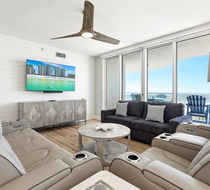 Sink into plush recliners and watch ocean views unfold through floor-to-ceiling windows in your bright, modern living space.
