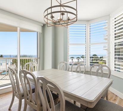 Gather around your elegant dining table while soaking in stunning ocean views through floor-to-ceiling windows that frame the perfect beach getaway.