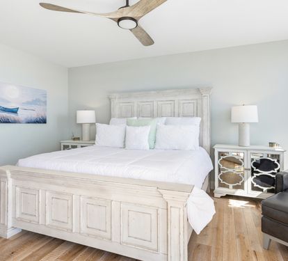 Sink into crisp white linens and coastal charm in your serene bedroom, where gentle sea breezes from the ceiling fan ensure restful nights.