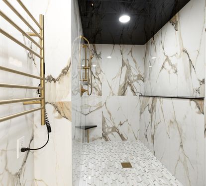 Luxurious marble shower with gold fixtures and heated towel rails creates your personal spa sanctuary.