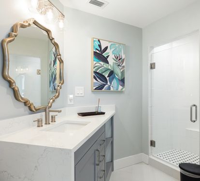 Your elegant bathroom features a spa-like shower, stylish vanity with gold fixtures, and beautiful botanical artwork for a refreshing retreat.