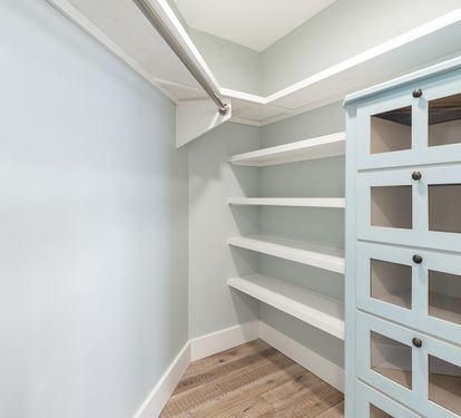 Your private walk-in pantry offers organized storage with built-in shelving and glass-front cabinets for all your culinary essentials.