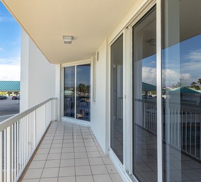 Step onto your private balcony where tiled floors and glass doors frame peaceful views of the surrounding area below.
