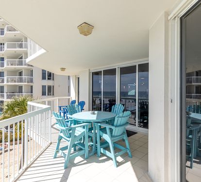 Your private balcony features turquoise dining chairs and table where you can enjoy meals with ocean breezes and coastal views.