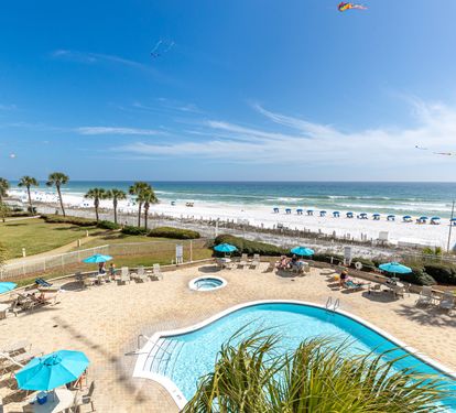 Stunning beachfront pool deck with crystal-clear waters, tropical palms, and pristine white sand stretching to the horizon.