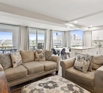 Sink into plush sofas in your bright living space, where city views through floor-to-ceiling windows create the perfect backdrop for relaxation.