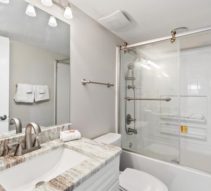 Unwind in your sleek bathroom featuring marble counters, modern fixtures, and a refreshing shower-tub combo after exploring the city.
