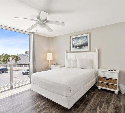 Your peaceful bedroom features crisp white linens, coastal charm, and a bright window where morning light gently wakes you.
