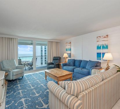 Unwind in your oceanfront living room where blue-toned furniture and coastal artwork create a soothing retreat with stunning balcony views.