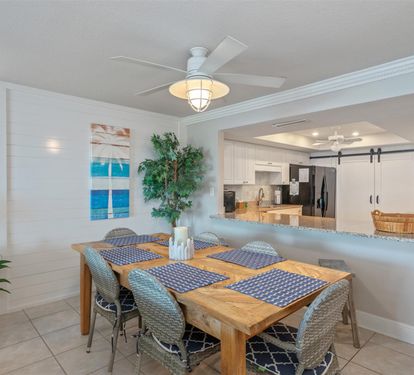 Gather around your stylish dining table for memorable meals together in this open, coastal-themed space with ocean artwork.