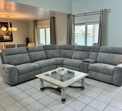Sink into your spacious sectional sofa and unwind while enjoying stunning water views through floor-to-ceiling windows in this elegant living space.