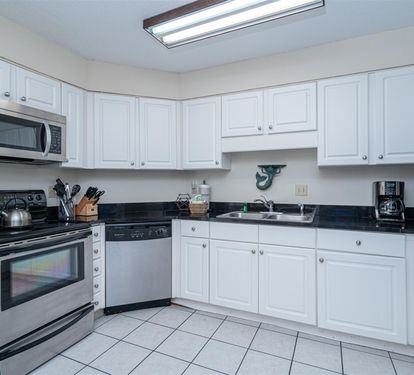 Your fully equipped kitchen features crisp white cabinets, granite countertops, and stainless steel appliances, perfect for preparing family meals during your stay.