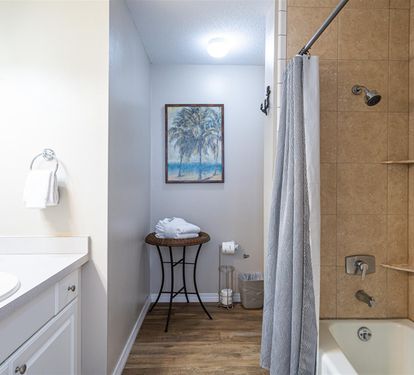 Unwind in your spa-like bathroom with a deep soaking tub, rainfall shower, and coastal artwork creating tranquil vibes.