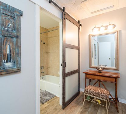 Unwind in your coastal-themed bathroom featuring a vintage vanity and sliding barn door that adds rustic charm to your private retreat.
