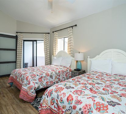 Sink into comfort with two plush beds adorned in vibrant floral linens, where natural light streams through elegant curtains.