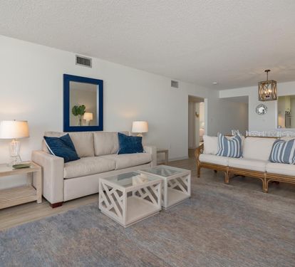 Relax in this spacious living room featuring plush seating, coastal blue accents, and elegant lighting that creates your perfect seaside retreat.