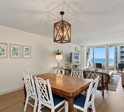 Gather around your elegant dining table while soaking in stunning ocean views through floor-to-ceiling windows in this beautifully appointed space.