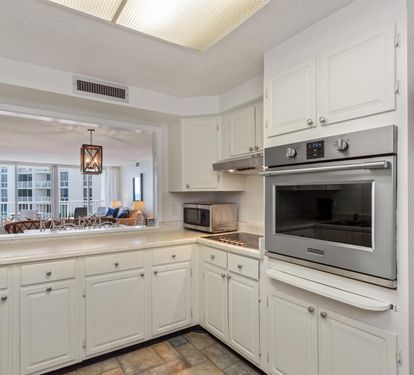 Your fully equipped kitchen features stainless steel appliances and white cabinetry, with a pass-through opening to the bright living area.