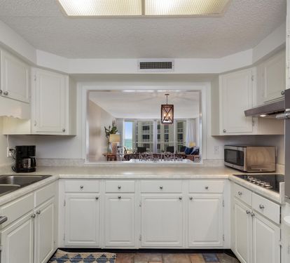 Prepare delicious meals in this bright, fully-equipped kitchen featuring white cabinetry and modern appliances.