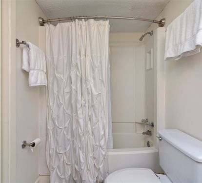 Step into your pristine bathroom with plush white towels and a relaxing tub combo for unwinding after busy days exploring.