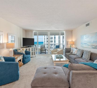 Relax in your ocean-view living room with plush seating, coastal decor, and balcony access to stunning sea views.