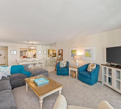 Sink into plush sofas and vibrant blue chairs while coastal artwork and soft lighting create your perfect retreat atmosphere.