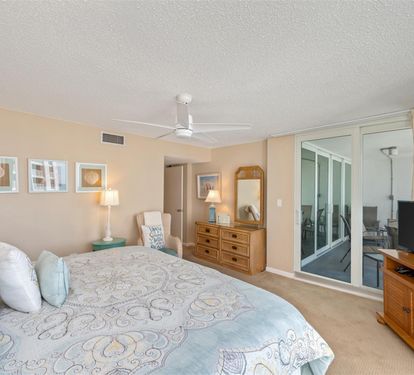 Unwind in your serene bedroom with soft coastal colors, ceiling fan comfort, and sliding doors opening to your private balcony retreat.