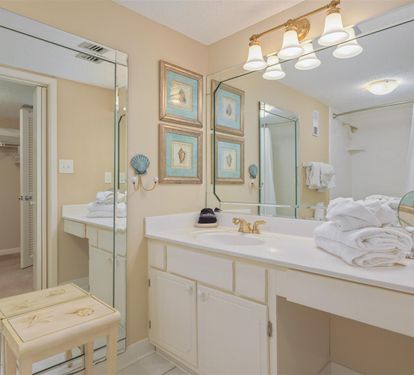 Your spacious bathroom features dual vanities, soft lighting, and coastal artwork, creating a serene space for your morning and evening routines.