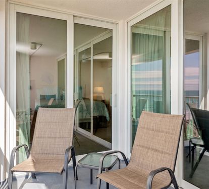 Unwind on your private balcony with comfortable seating, where floor-to-ceiling windows frame your perfect coastal retreat.