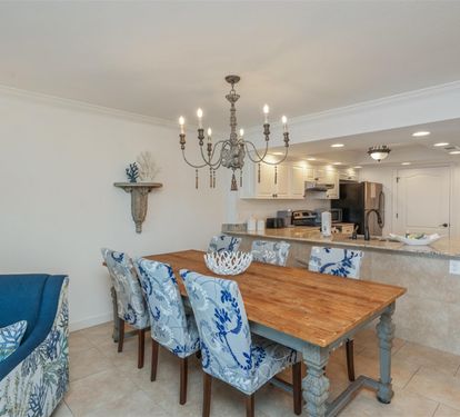 Gather around your coastal dining table for memorable meals beneath an elegant chandelier, with the open kitchen ready for easy meal prep.