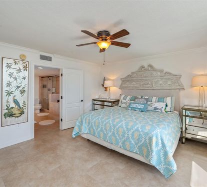 Drift off in your coastal-inspired bedroom with ocean-themed linens, mirrored nightstands, and gentle ceiling fan breezes creating the perfect sleep sanctuary.