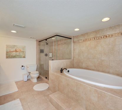 Luxurious spa-like bathroom with deep soaking tub, glass shower, and elegant travertine finishes for your ultimate relaxation.
