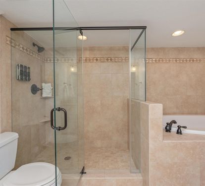 Unwind in your luxurious bathroom featuring a spacious glass shower and relaxing soaking tub with elegant neutral tones.