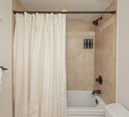 Unwind in your private bathroom featuring a full tub-shower combo and elegant neutral tones for your relaxation.