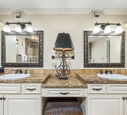 Pamper yourself at this elegant double vanity with granite countertops, ornate mirrors, and charming built-in seating area for your morning routine.