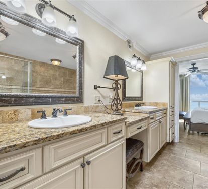Indulge in your private spa-like bathroom with elegant granite counters, double vanity, and stunning sea views beyond.