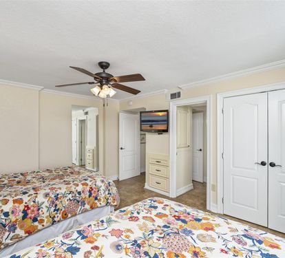 Rest peacefully in your bright bedroom featuring twin beds with cheerful floral linens, ceiling fan, and ample storage space.