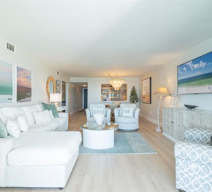 Sink into plush coastal comfort with soft sea-green accents and beach artwork surrounding you in this serene living space.